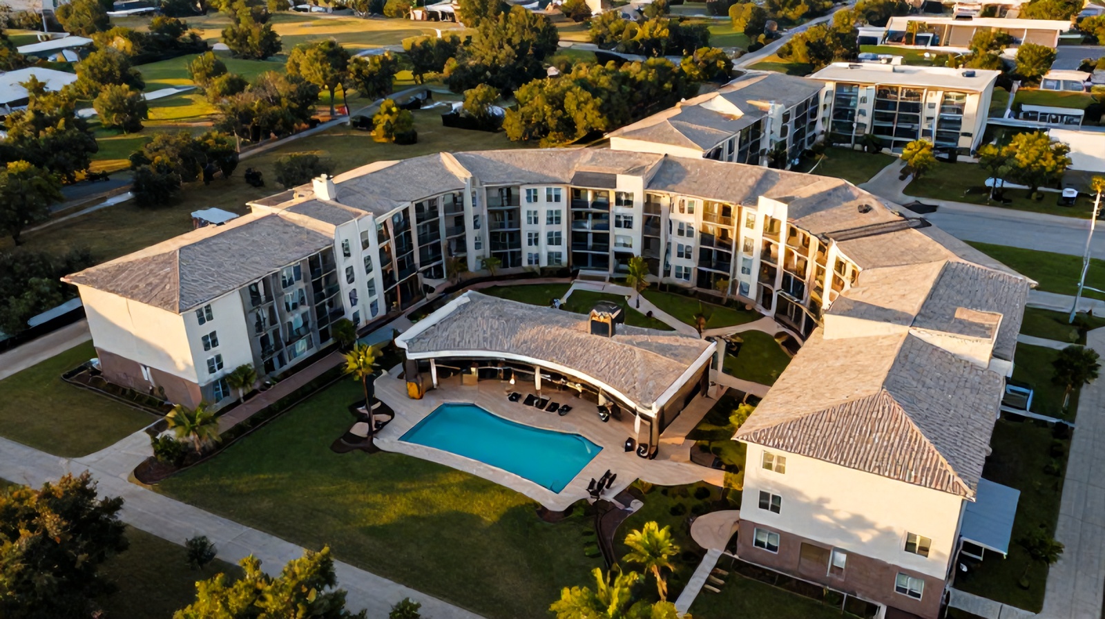 Aerial view of a modern Austin apartment complex with pool and landscaped courtyards at golden hour