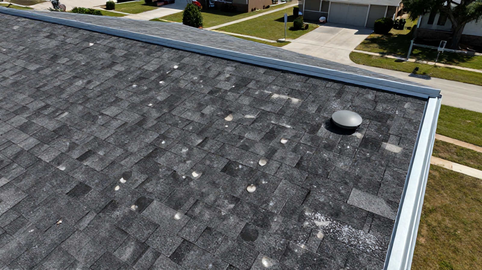 Close aerial detail of individual hail impact marks and granule loss on shingles