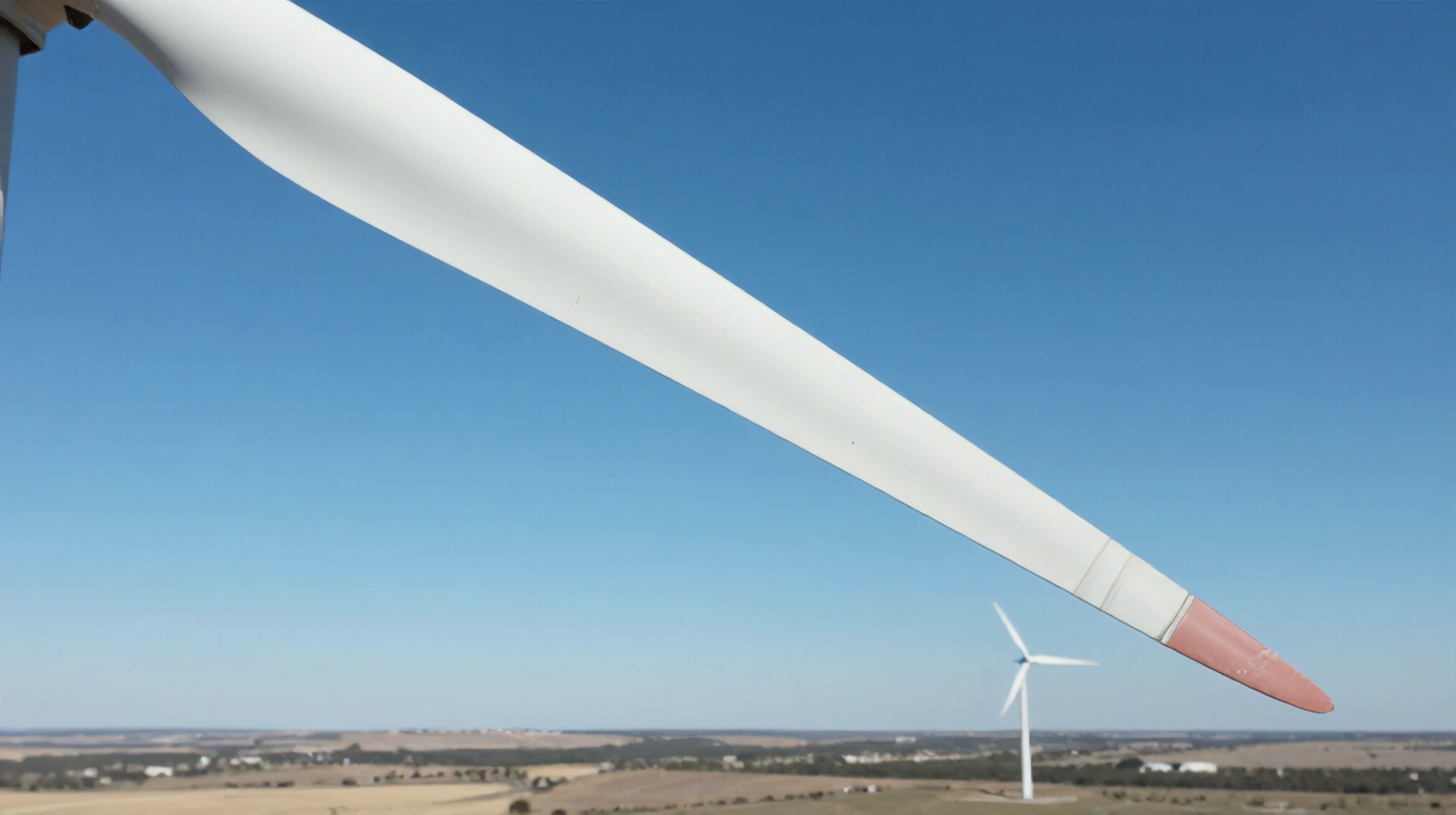 Close aerial inspection view of a wind turbine blade showing surface erosion and cracks
