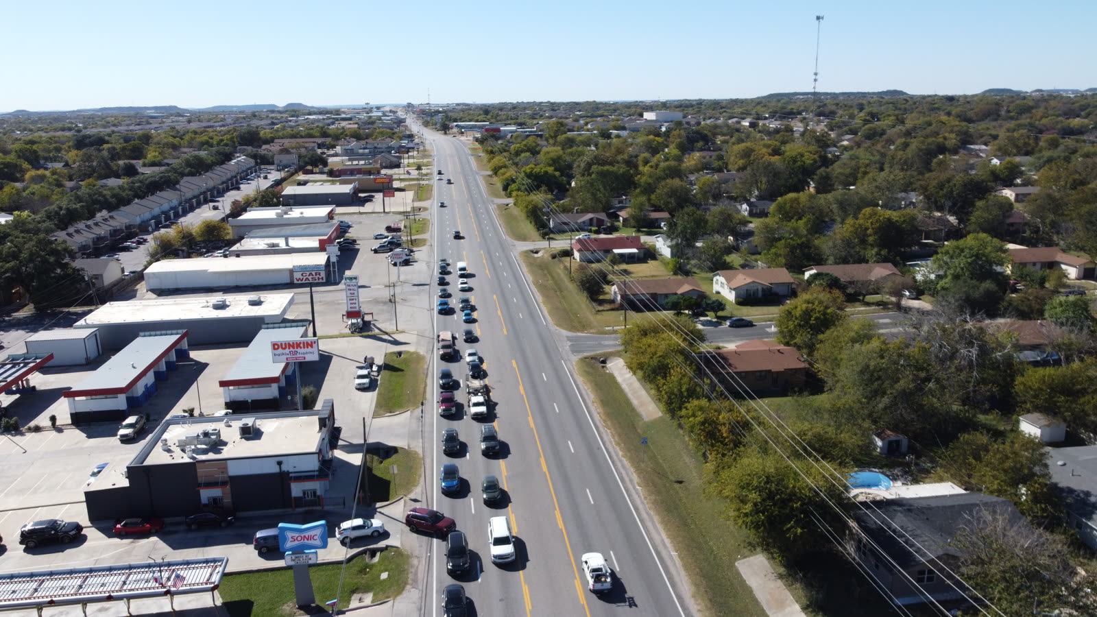 Low-altitude aerial view of a suburban Austin commercial warehouse rooftop during an authorized inspection flight